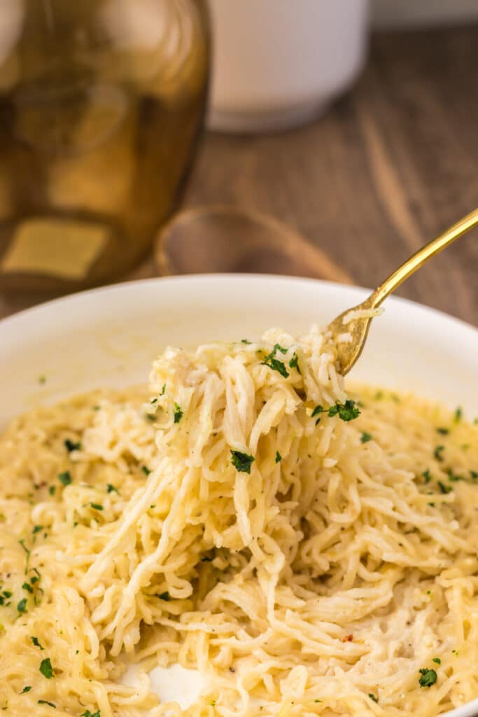 Fork lifting a bite of creamy garlic parmesan ramen from the bowl