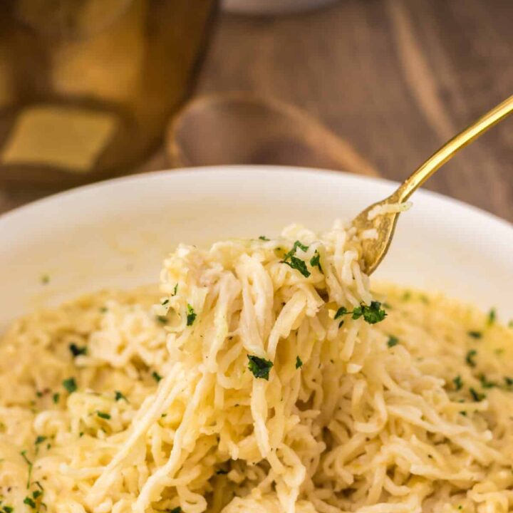 Fork lifting a bite of creamy garlic parmesan ramen from the bowl