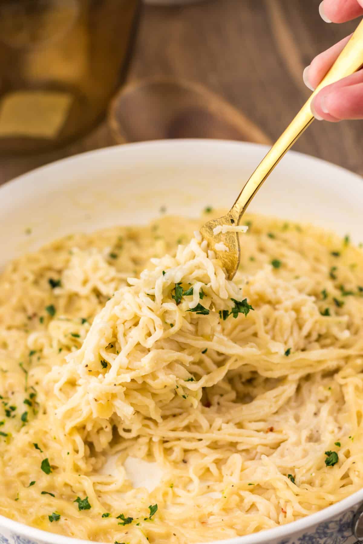 Fork lifting a bite of creamy garlic parmesan ramen from the bowl