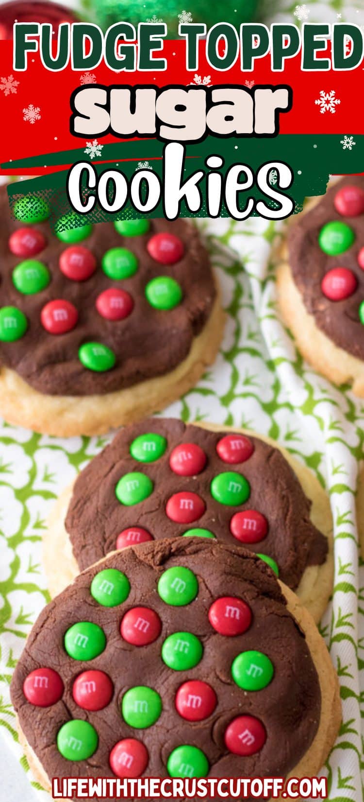 Thick sugar cookies topped with glossy chocolate fudge and red & green holiday candies on parchment paper