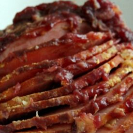 Slow cooker ham glazed with pineapple and cranberry sauce, sliced on a holiday platte