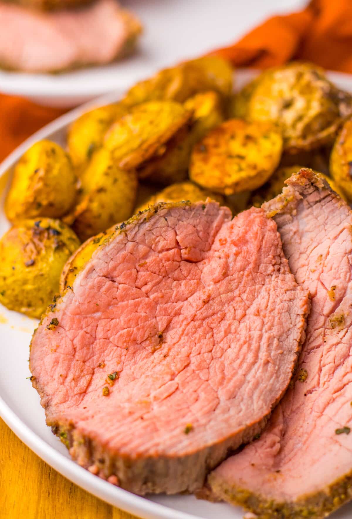 Close-up of perfectly cooked eye of round roast showing a juicy, pink center.