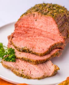 Tender eye of round roast sliced and displayed on a serving plate.