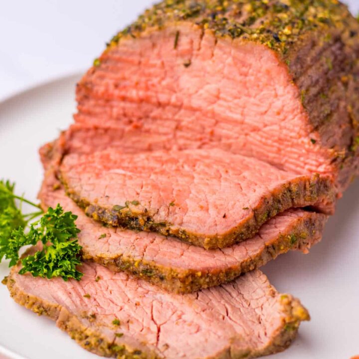 Tender eye of round roast sliced and displayed on a serving plate.
