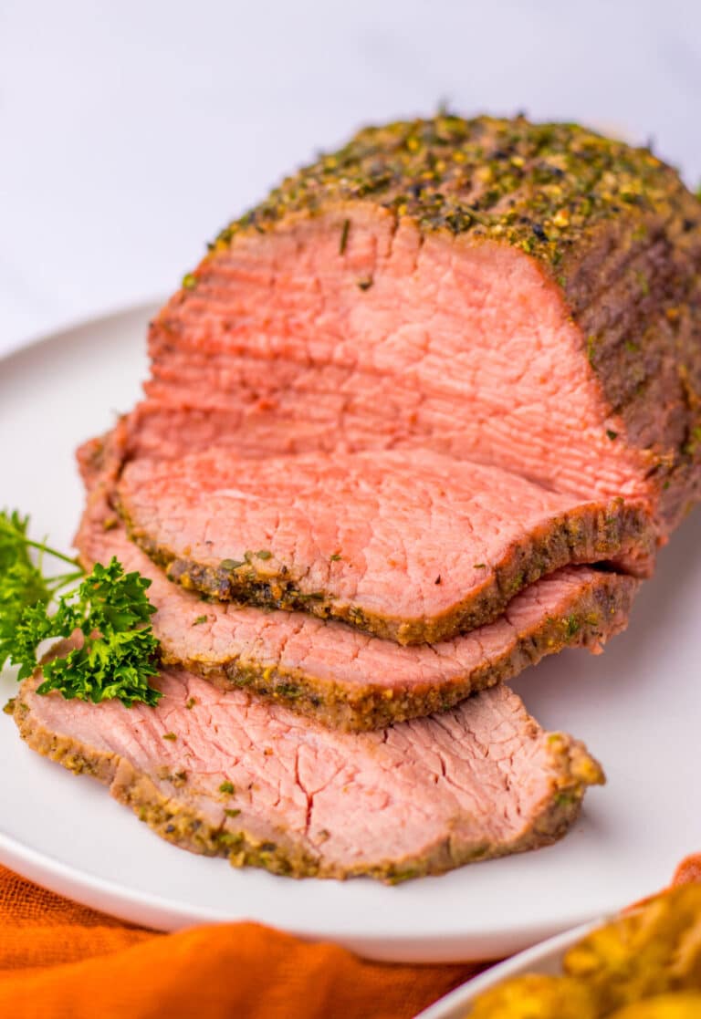 Tender eye of round roast sliced and displayed on a serving plate.