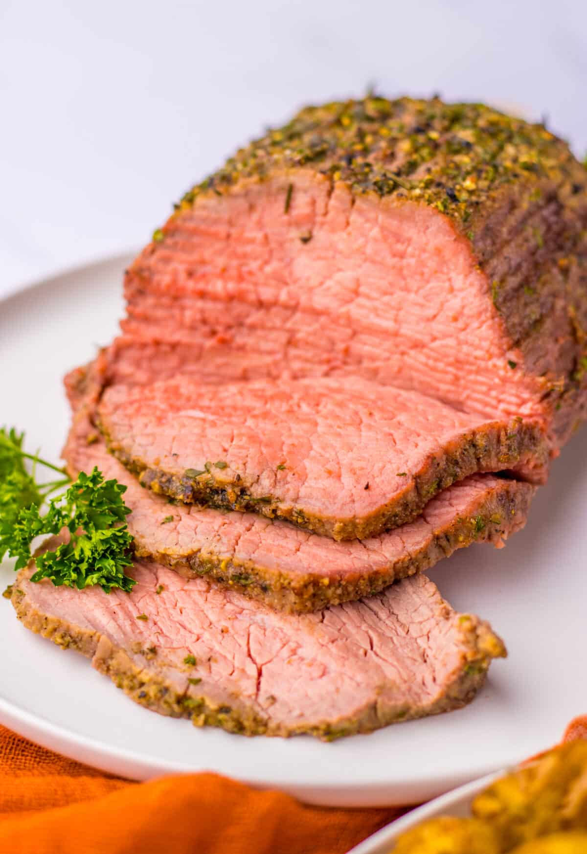 Tender eye of round roast sliced and displayed on a serving plate.