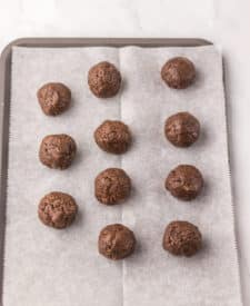 Raspberry brownie bombs rolled into balls and arranged on a parchment-lined tray.