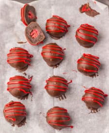Chocolate-covered raspberry brownie bombs drizzled with red chocolate.