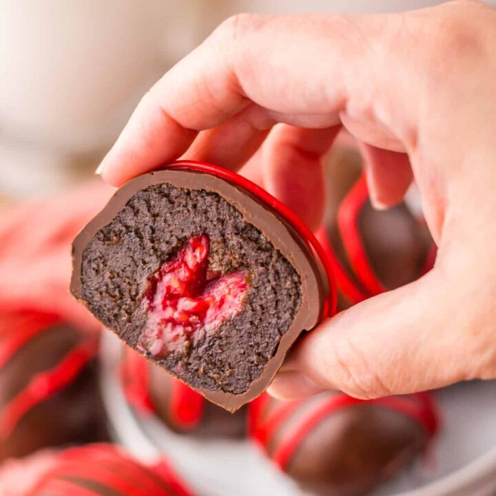 Hand holding a raspberry brownie bomb showing the fudgy interior.