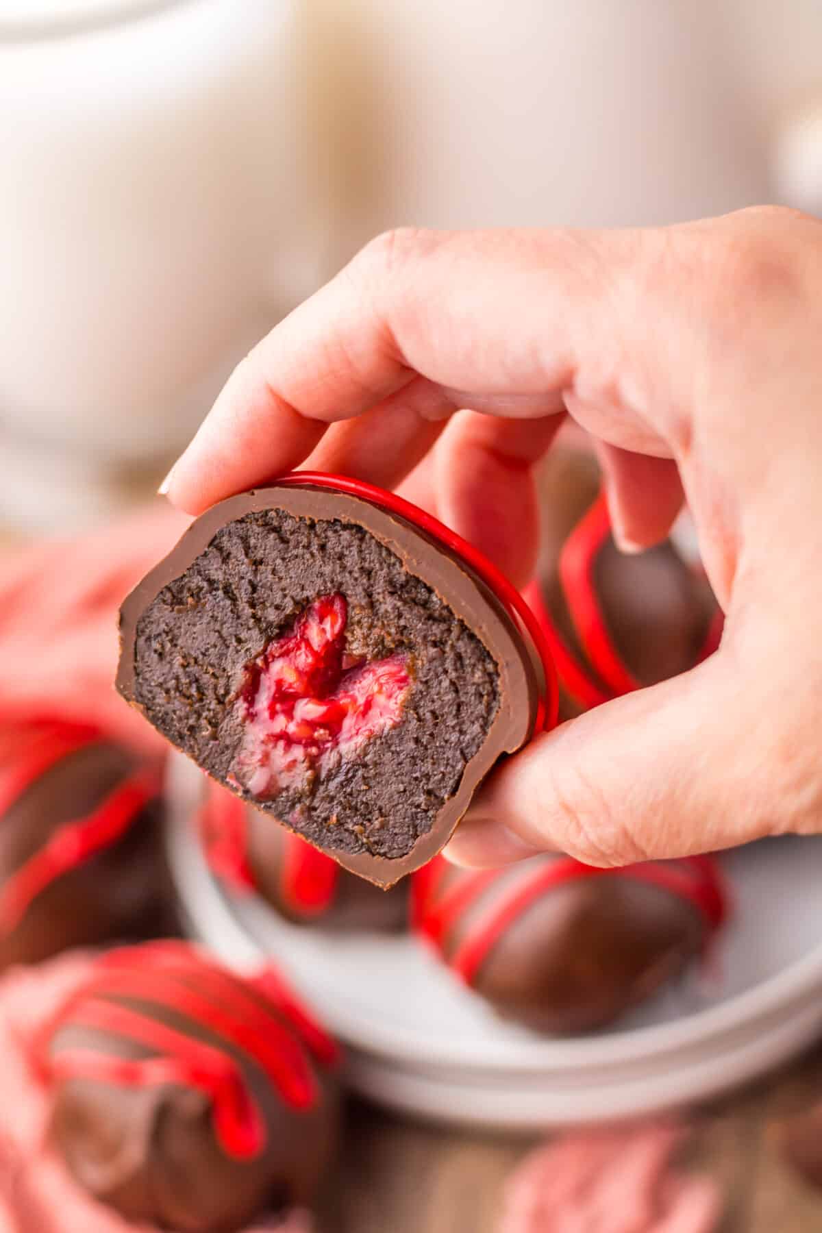 Hand holding a raspberry brownie bomb showing the fudgy interior.