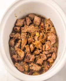 Close-up of slow cooker Dr Pepper steak bites simmering in a rich, sticky sauce.