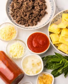 Ingredients for slow cooker ravioli lasagna including ravioli, sauce, and cheese