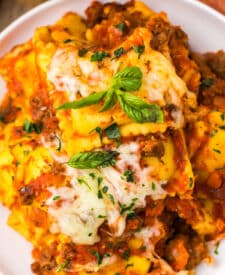 Slow cooker ravioli lasagna topped with melted cheese and fresh basil