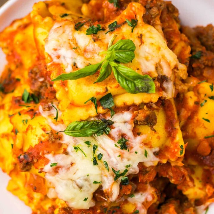Slow cooker ravioli lasagna topped with melted cheese and fresh basil