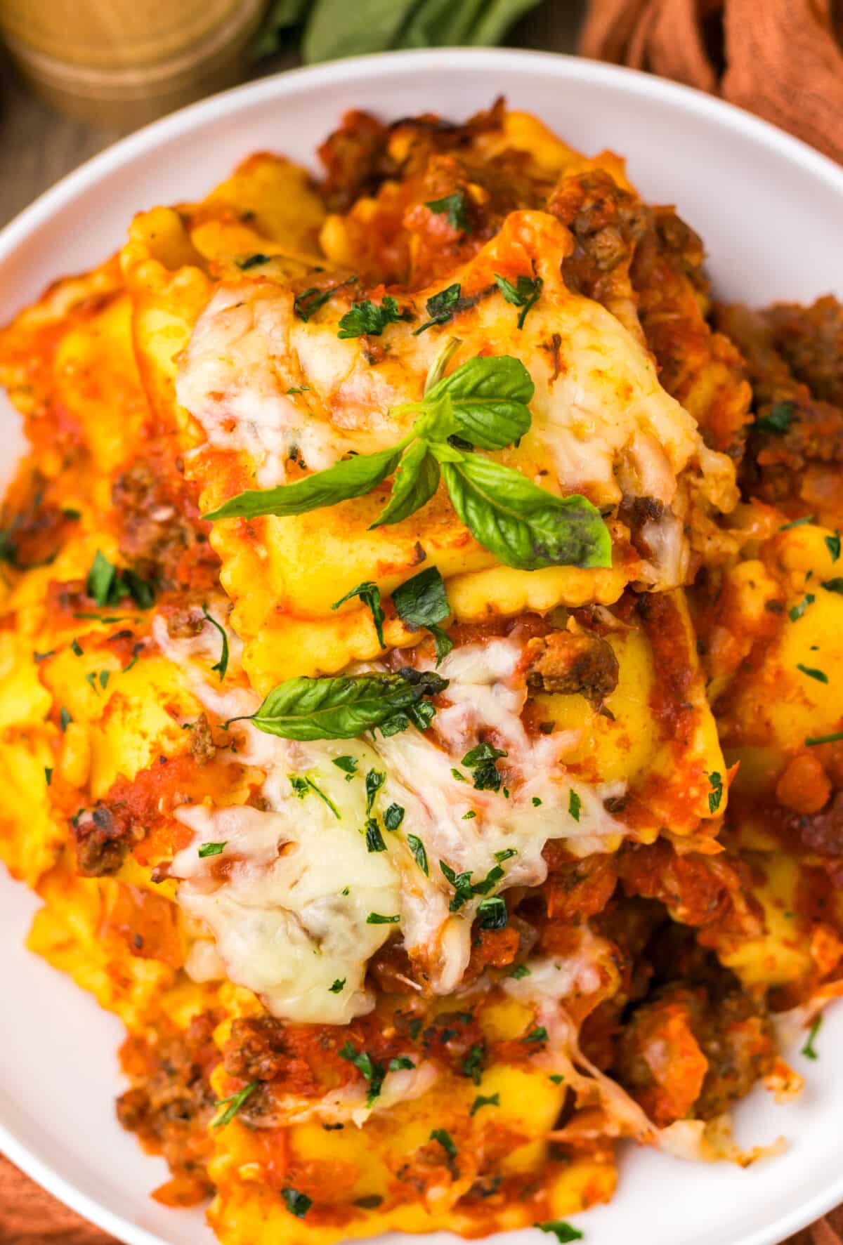 Slow cooker ravioli lasagna topped with melted cheese and fresh basil
