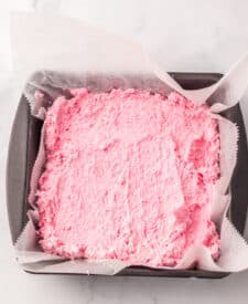 Strawberry Cool Whip candy mixture spread evenly into a parchment-lined pan.