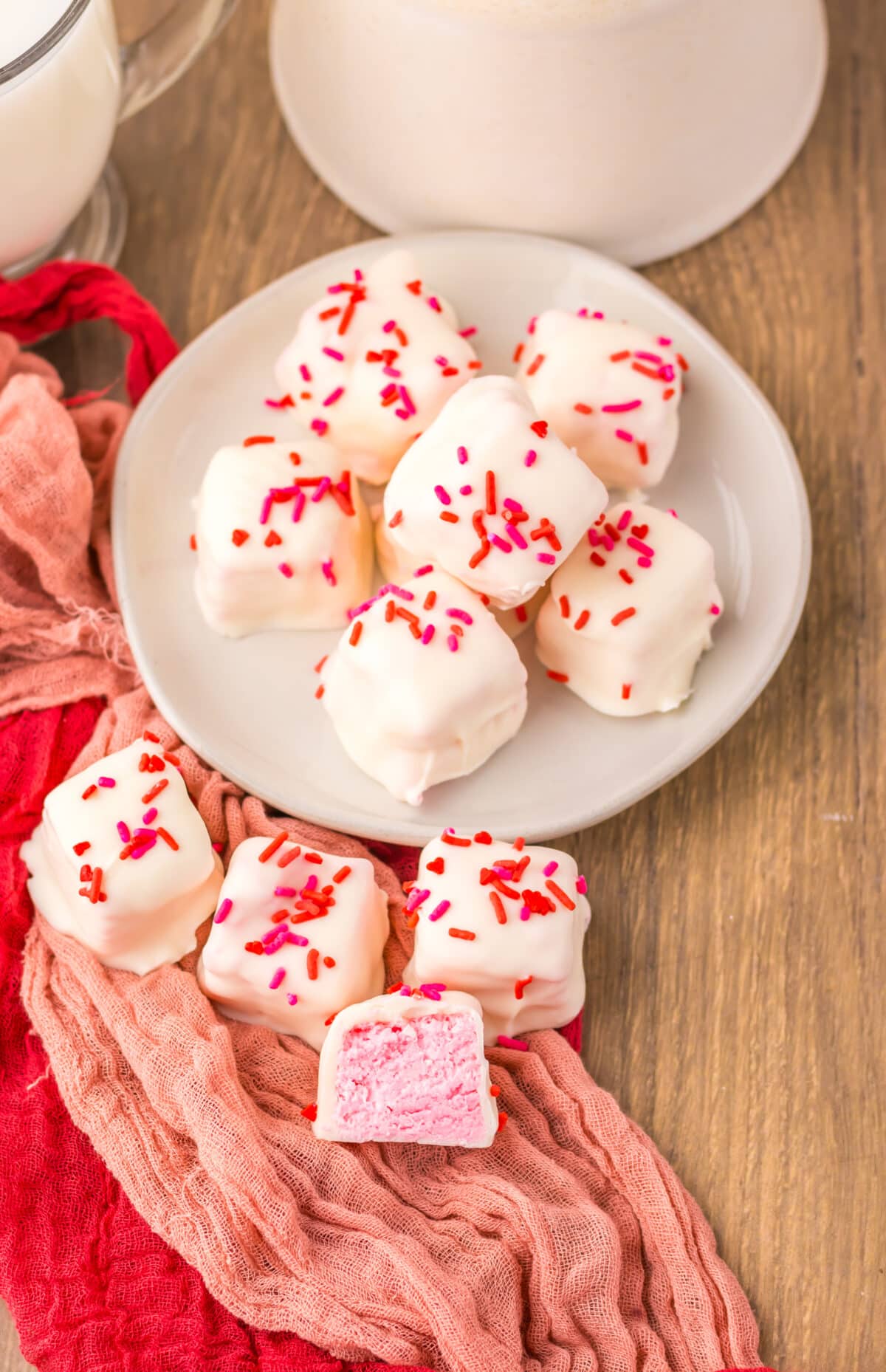 Close-up of strawberry Cool Whip candy squares with white chocolate coating and red sprinkles.