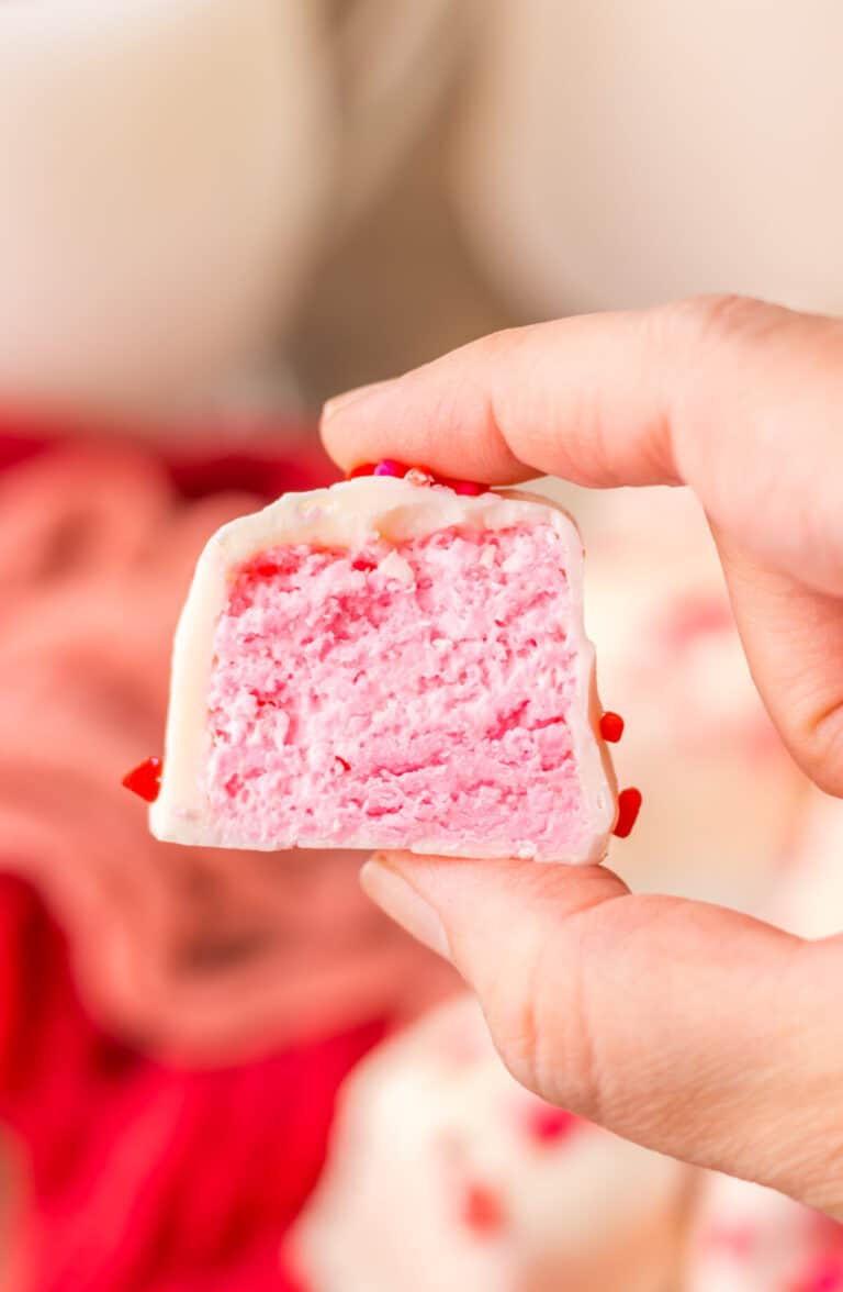 Cross-section view of strawberry Cool Whip candy showing pink filling and white chocolate layer.