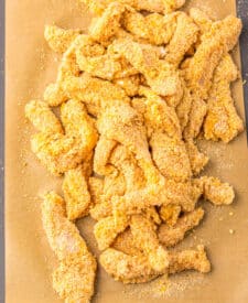 Raw breaded chicken fries lined up before cooking.