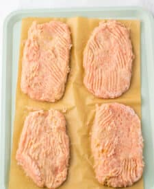 Seasoned chicken patties arranged on a baking sheet ready to bake.