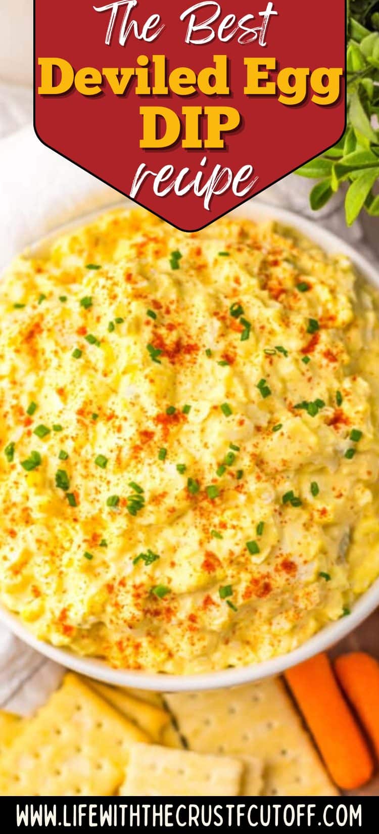 Deviled egg dip served in a bowl with paprika and green onions with crackers for dipping