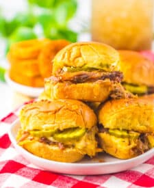 Slow cooker brisket sliders stacked together on a serving platter.