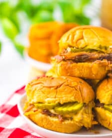 Slow cooker brisket sliders stacked together on a serving platter.