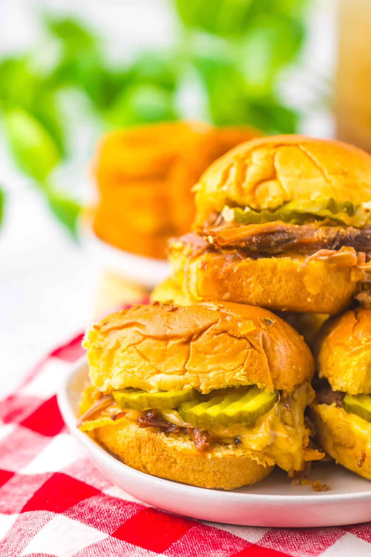 Slow cooker brisket sliders stacked together on a serving platter.