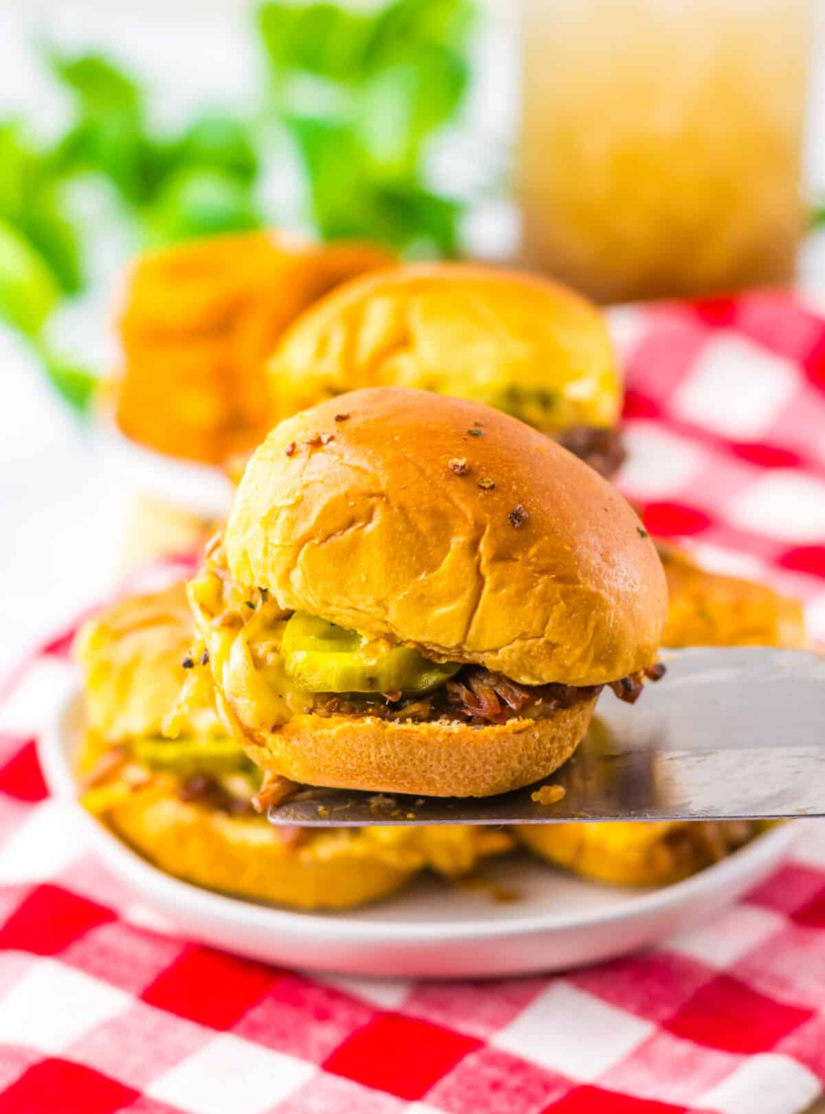 Slow cooker brisket sliders stacked together on a serving platter.