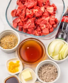 Ingredients for slow cooker Coca Cola beef tips including beef, Coca Cola, onions, and seasonings.