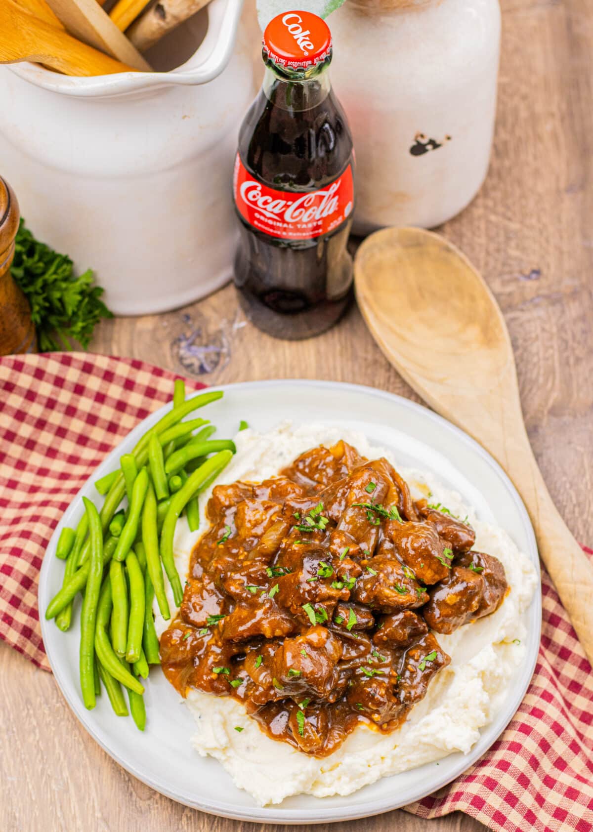 Coca Cola beef tips plated with a bottle of Coke in the background.