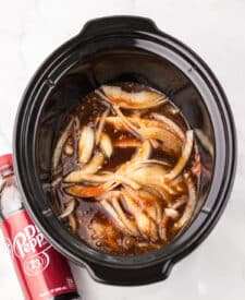 Pork chops cooking in the slow cooker with Dr Pepper sauce.