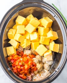 Nacho meatballs cooking in the slow cooker with cheese and sauce ingredients.