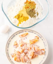 Raw chicken pieces seasoned in a bowl before breading.