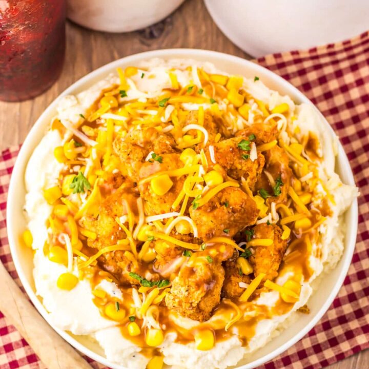 Copycat KFC Famous Bowl served with mashed potatoes, popcorn chicken, corn, gravy, and shredded cheese.