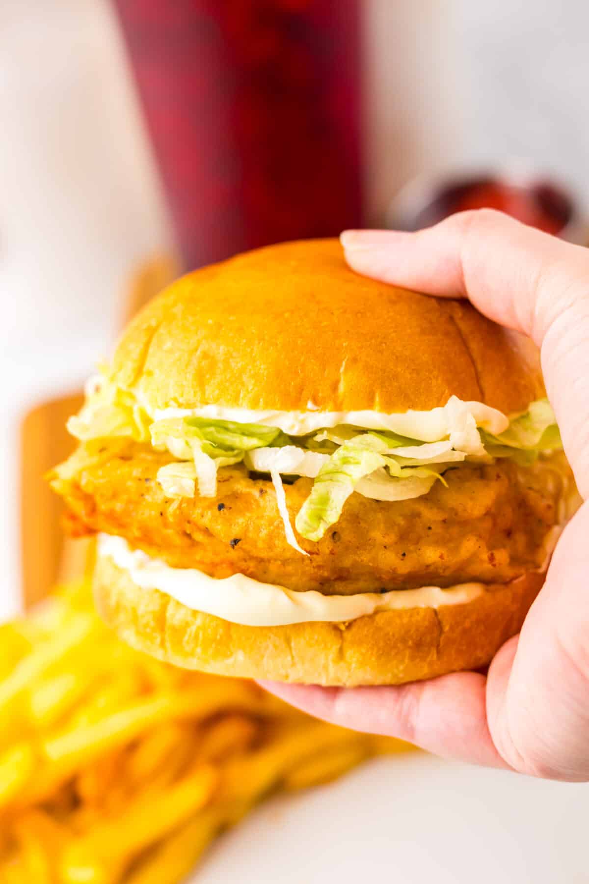 Hand holding a freshly assembled copycat McDonald’s McChicken sandwich.