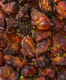 Honey BBQ riblets coated in sticky barbecue sauce in a baking dish.