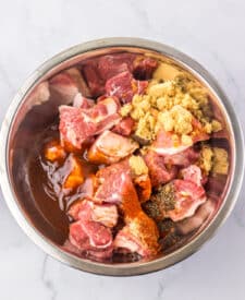 Raw riblets tossed in honey barbecue sauce in a mixing bowl.