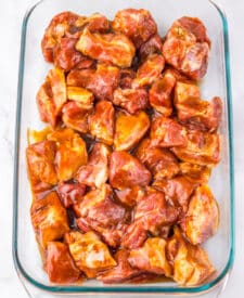 Honey BBQ riblets coated in sticky barbecue sauce in a baking dish.