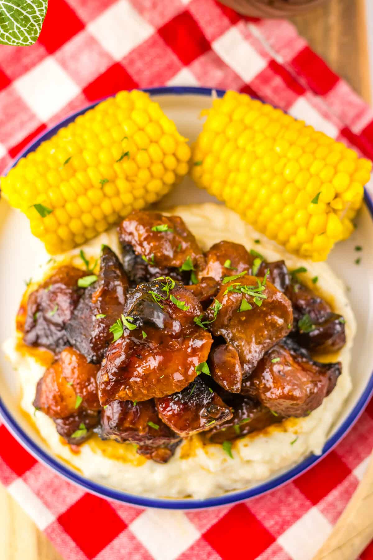 Honey BBQ riblets served over mashed potatoes with corn on the cob.