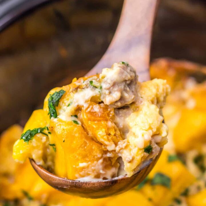 Close-up of slow cooker sausage gravy biscuit casserole being scooped with a spoon.