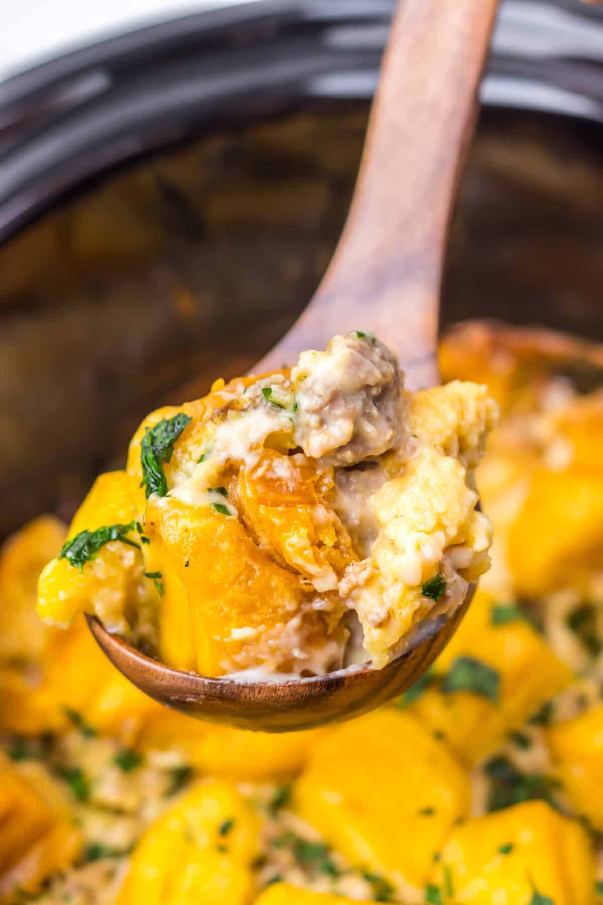 Close-up of slow cooker sausage gravy biscuit casserole being scooped with a spoon.