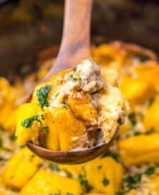 Close-up of slow cooker sausage gravy biscuit casserole being scooped with a spoon.