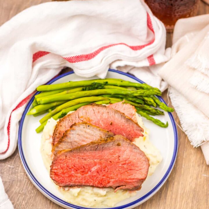 Air fryer eye of round roast served with mashed potatoes and green vegetables.