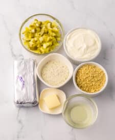 Ingredients for fried pickle dip including chopped pickles, cream cheese, sour cream, and seasonings.