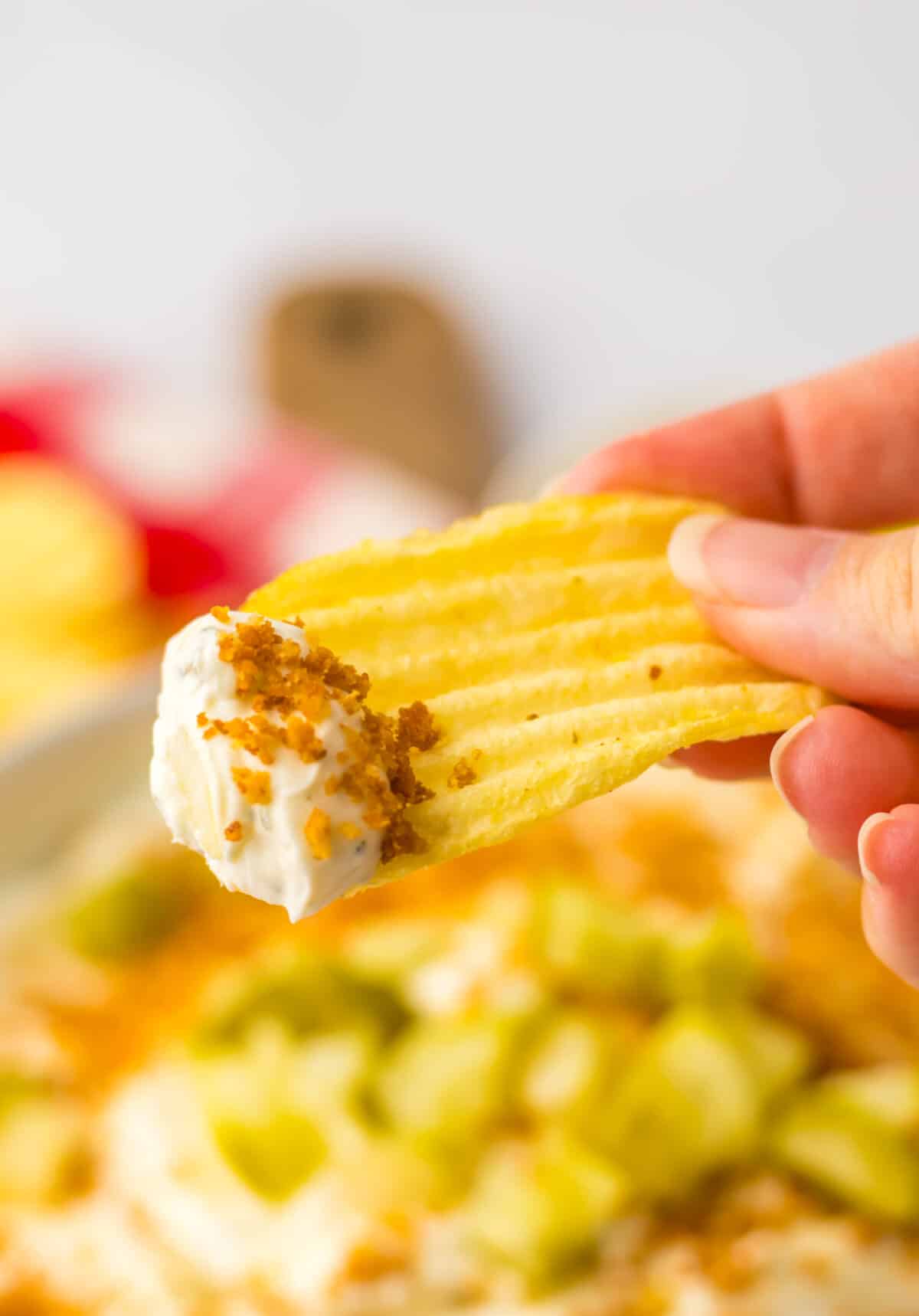 Ridged potato chip dipped into fried pickle dip.
