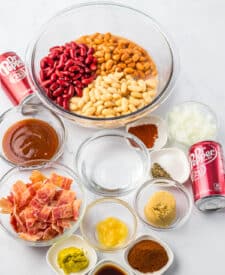Ingredients for slow cooker Dr Pepper baked beans including bacon, beans, brown sugar, barbecue sauce, and seasonings.
