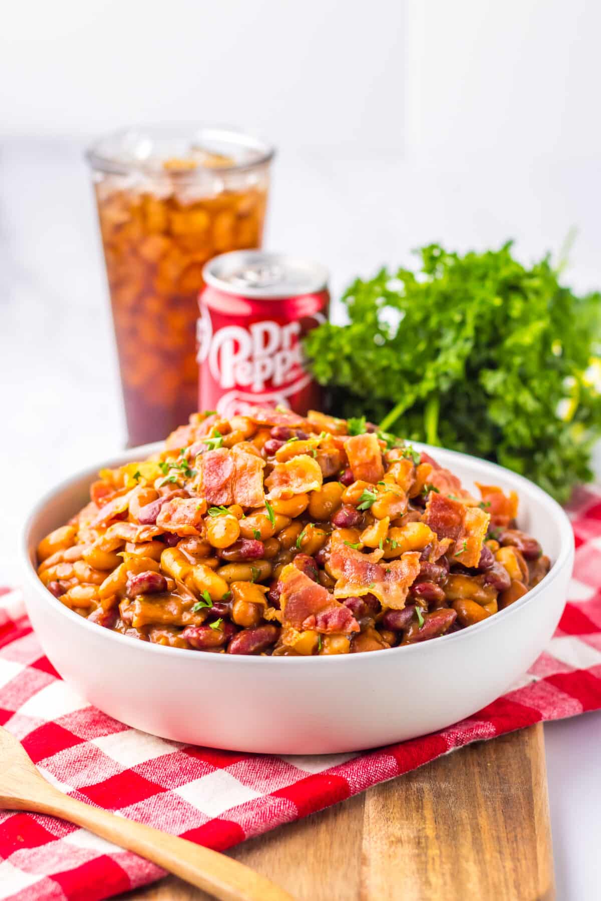 Serving of Dr Pepper baked beans with a soda in the background.