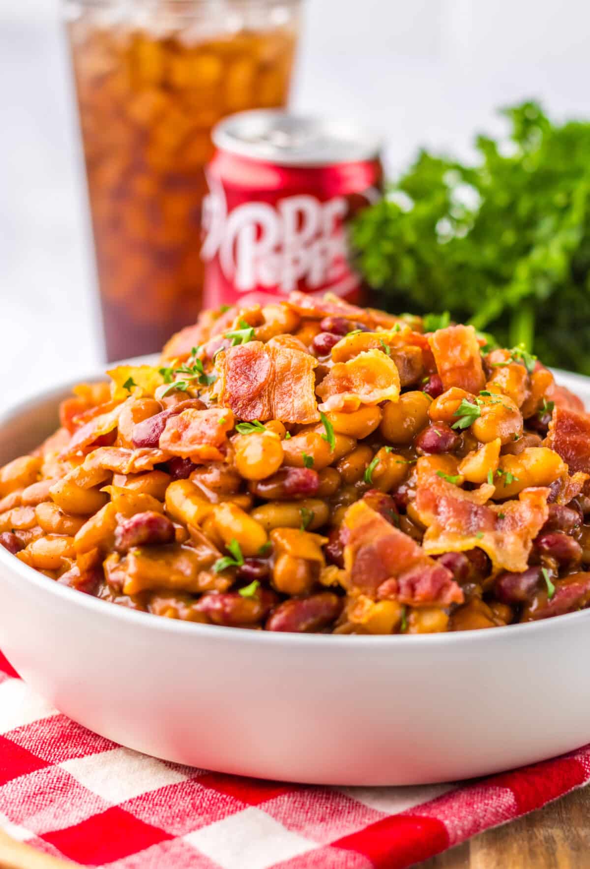 Serving of Dr Pepper baked beans with a soda in the background.
