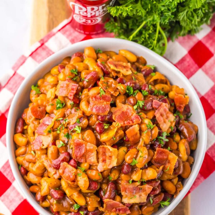 Bowl of baked beans topped with chopped bacon and parsley.